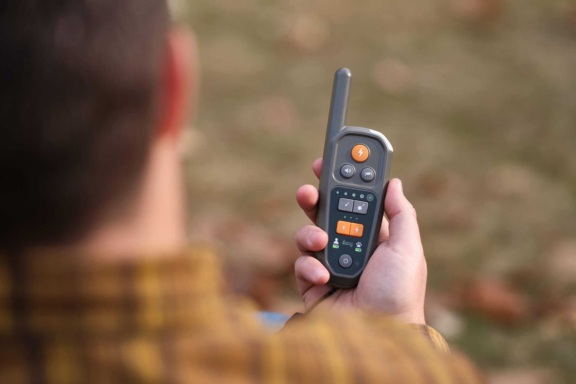 Over the shoulder view of a hand holding a Heel Virtual Dog Leash™ Roam 350™ Remote
