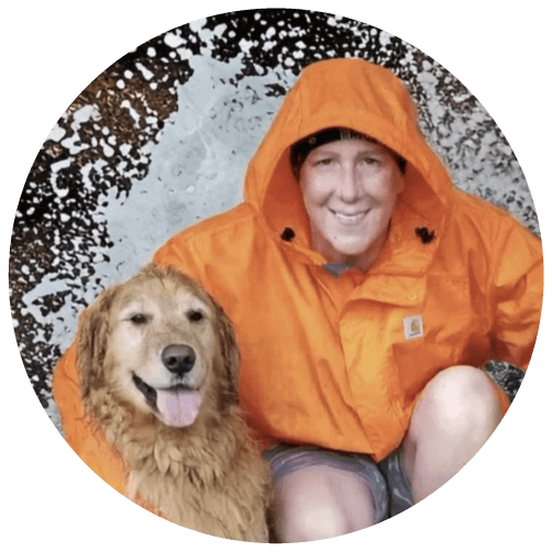 Woman wearing an orange raincoat and Golden Retriever being splashed by water from behind
