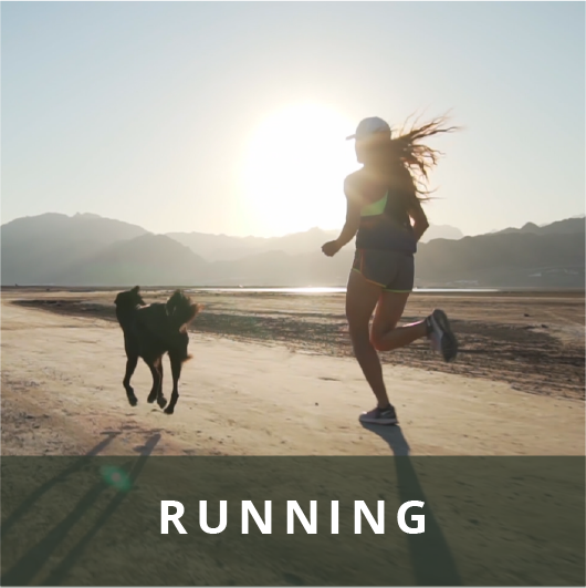 Woman running with her dog and mountains in the background